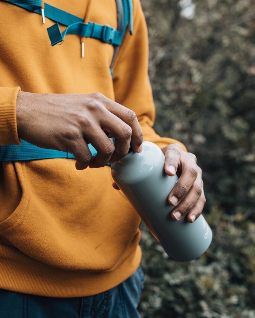 mid-section-man-opening-lid-water-bottle